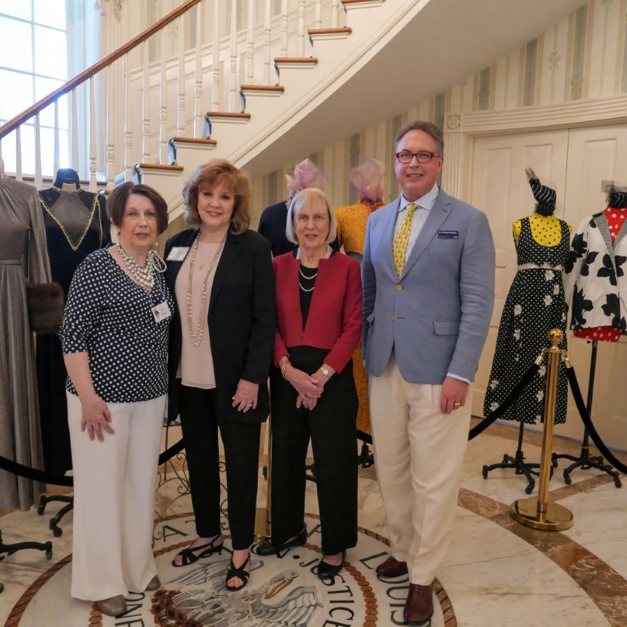 4 individuals standing in front of costumes