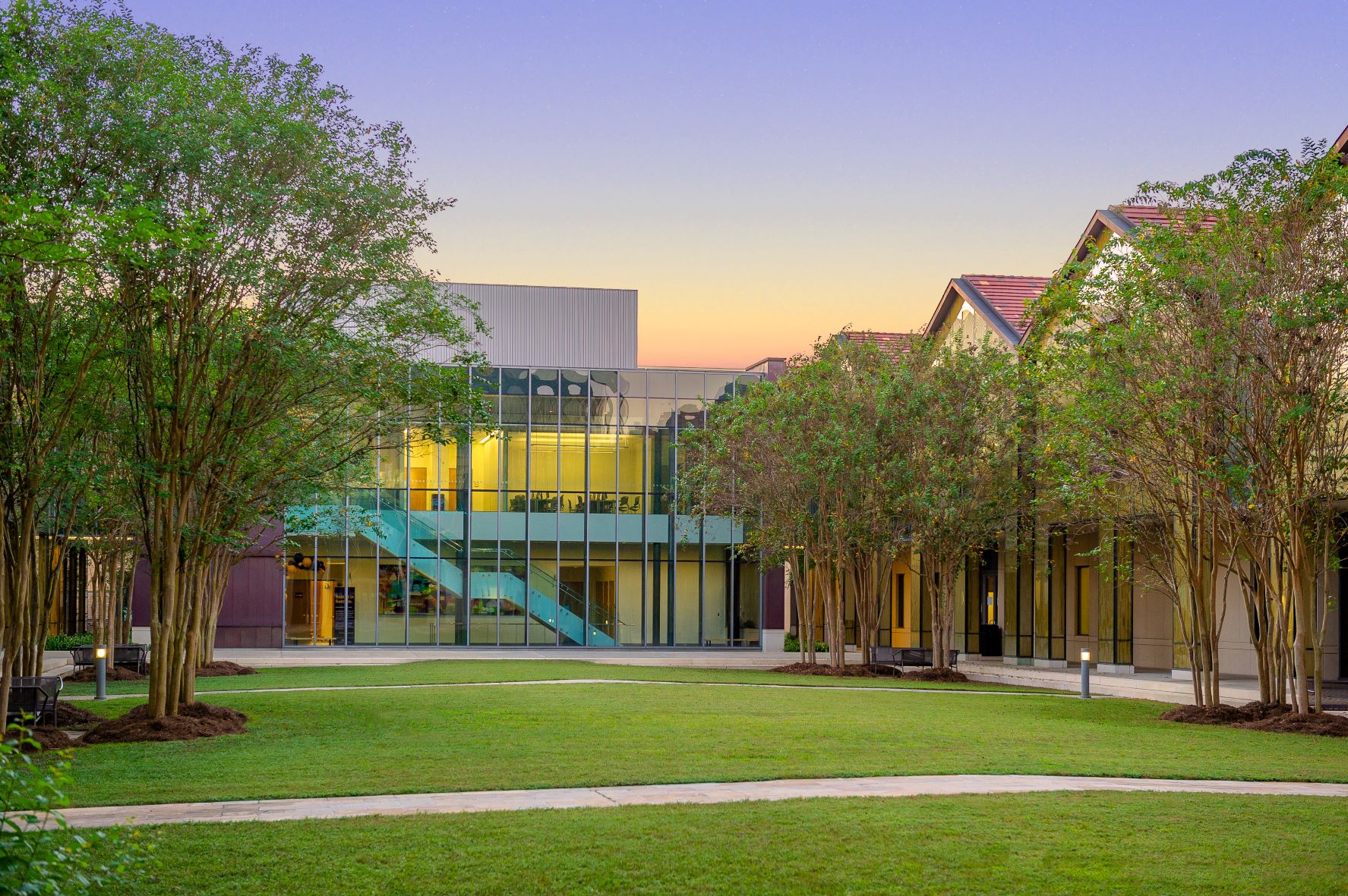 The courtyard of the Business Education Complex with a sunset behind in the auditorium building