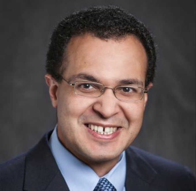 Mostafa Elseifi headshot he is wearing a dark suit in front of a dark grey background. 