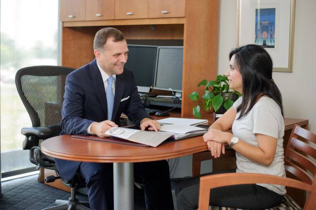 Male advisory speaks with female student at desk.