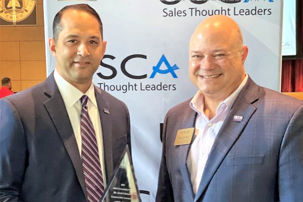 Jared Llorens hold award while standing next to Greg Accardo both men are wearing suits. 