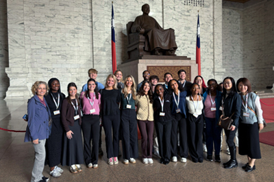 Faculty and students wear casual attire and stand in front of a statue in Taiwan.