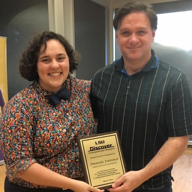 a studend professor holding an award