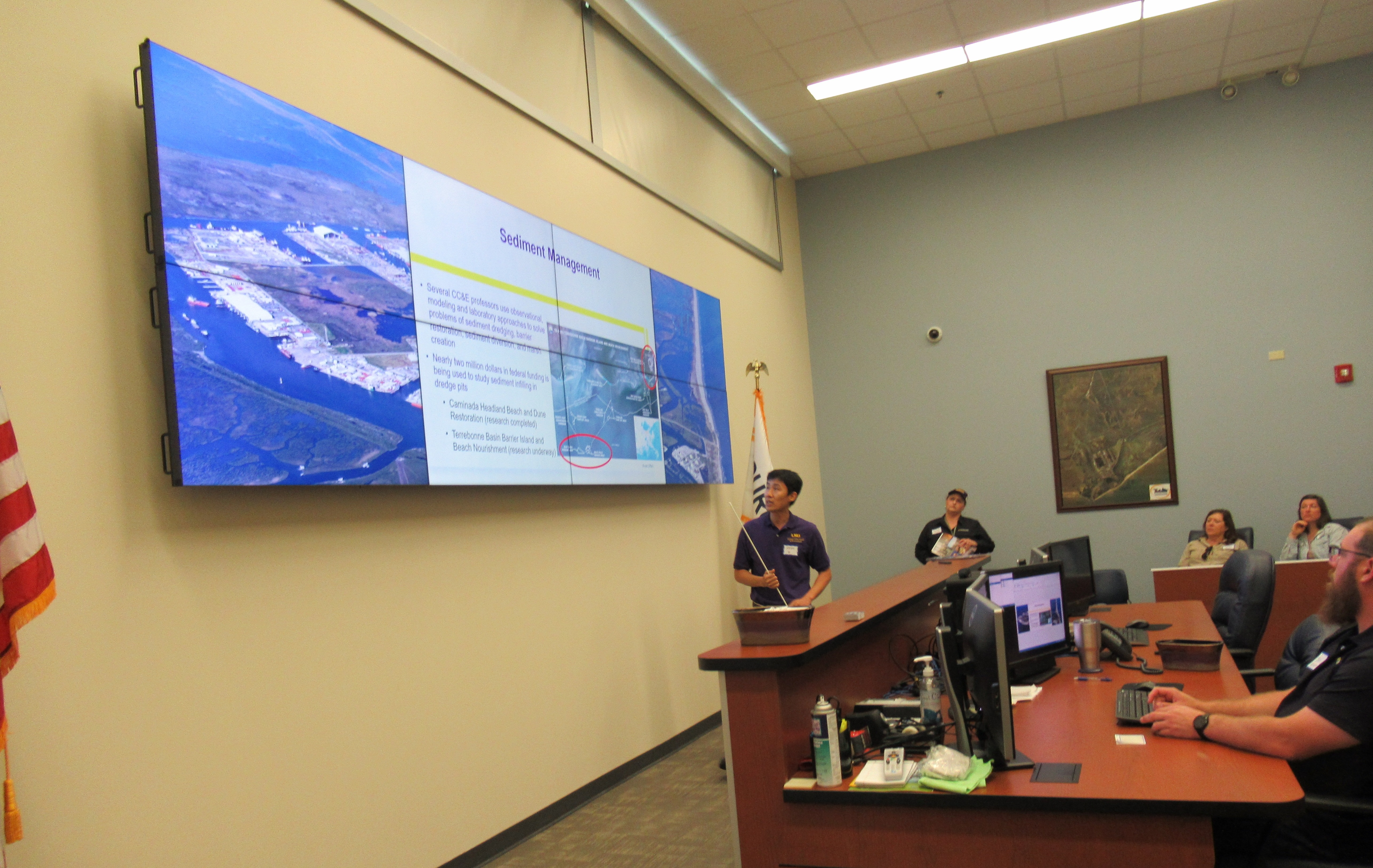 Kevin Xu points to a presentation on a wall in front of an audience