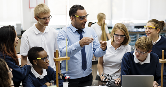 Photo of a science teacher conducting an experiment with children watching.