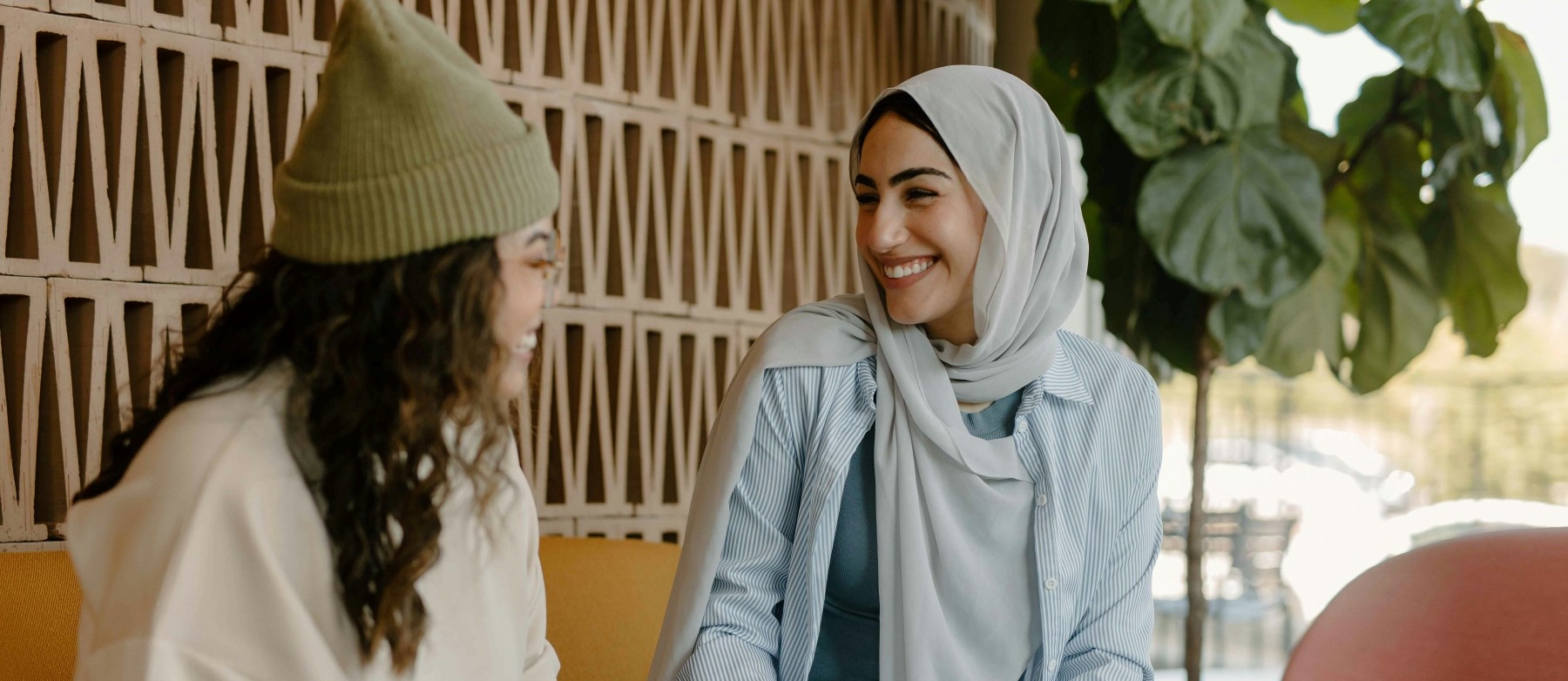 two women smile and chat in an office building