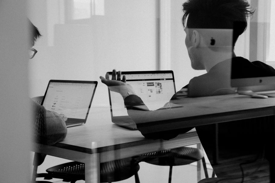 two people talk in front of a computer